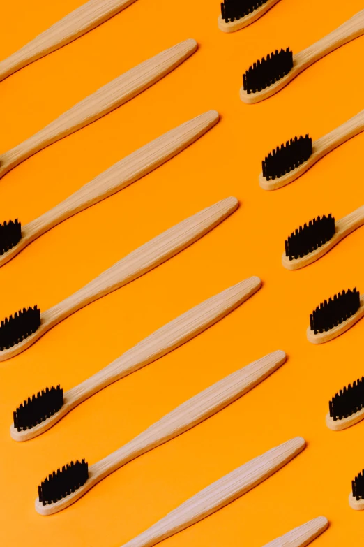 multiple rows of bamboo tooth brushes on a yellow background