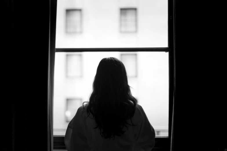 a person is seen from behind as they are standing by the window