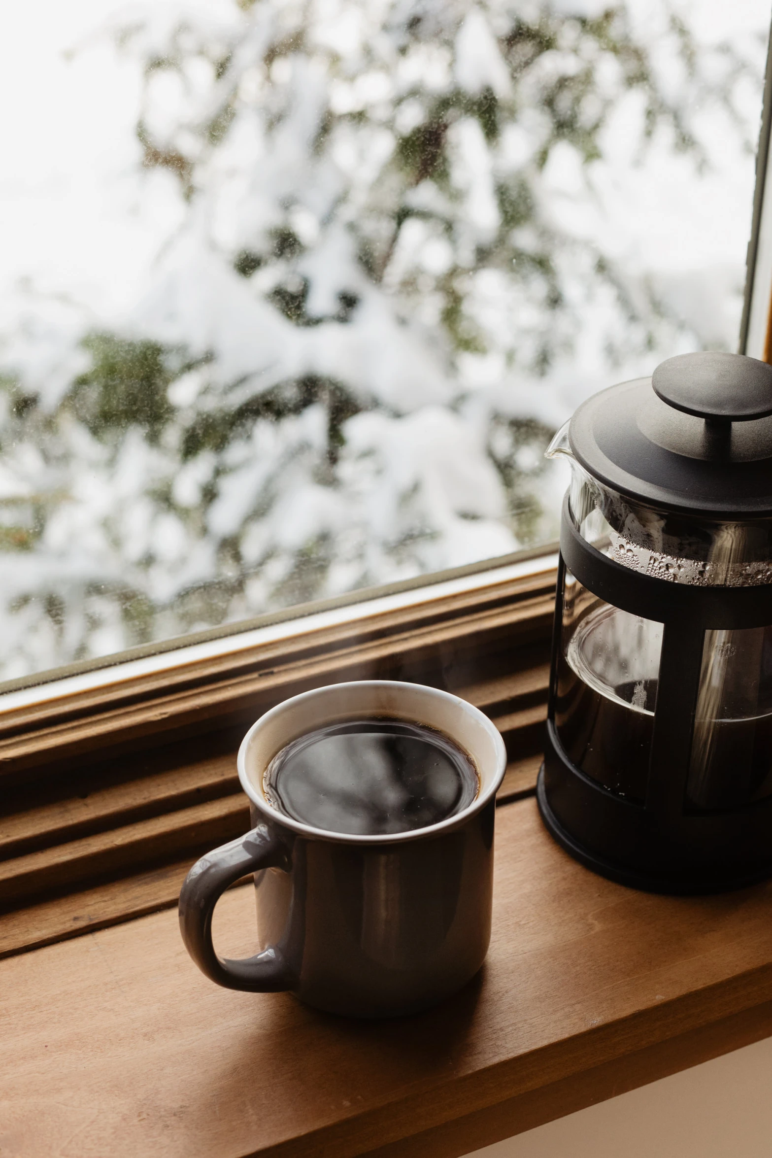 a silver cup with liquid in the middle next to a coffee pot