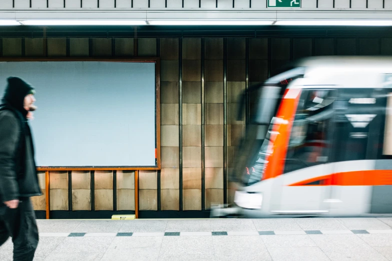 a man walking by a train in a subway station