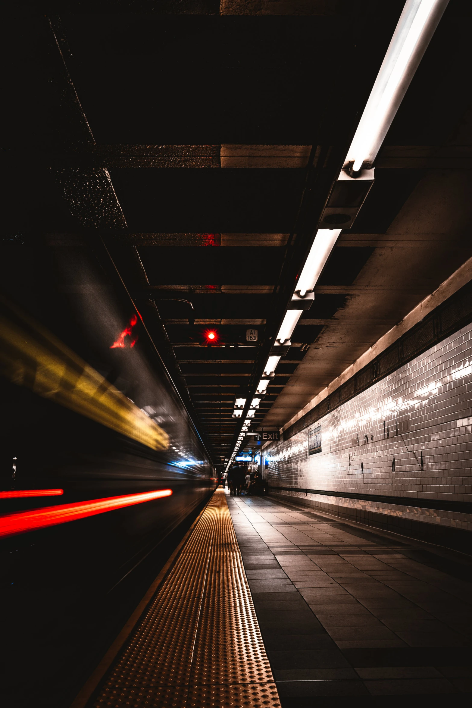 a dark tunnel is seen with red traffic lights