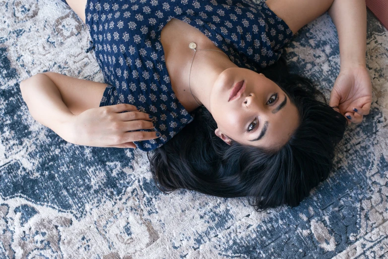a young woman laying on her back with one foot on a rug