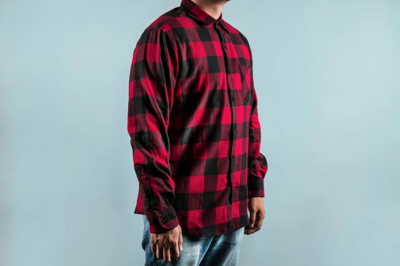 a man standing and looking off to the side wearing a red and black checkered shirt