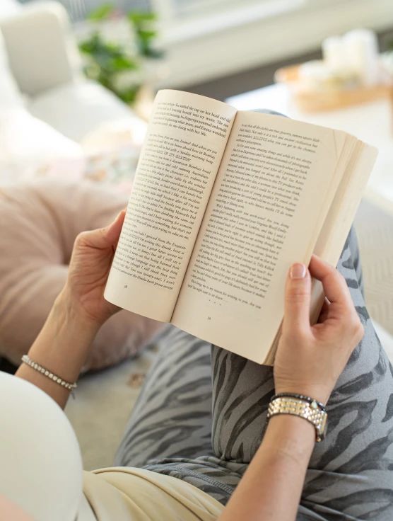 woman reading an open book in her living room