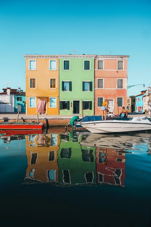 a boat sitting in a harbor with three colored houses