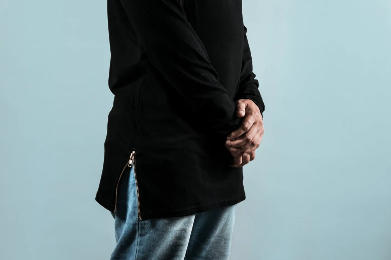 a man in an oversized black jacket standing with his hands on his hip