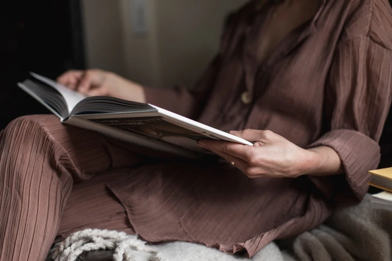 an older woman reading a book on a chair