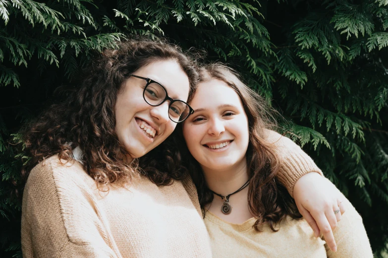 two girls pose for a po, one is hugging the other