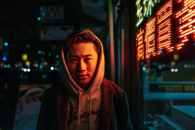 a guy in hoodie outside a business with lights and signs