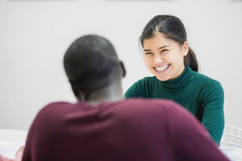 a woman smiling at another person in the room