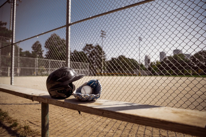 a baseball and a catcher's mitt next to a fence