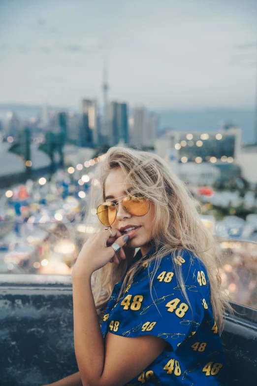 a woman in yellow sunglasses and a blue dress is smoking