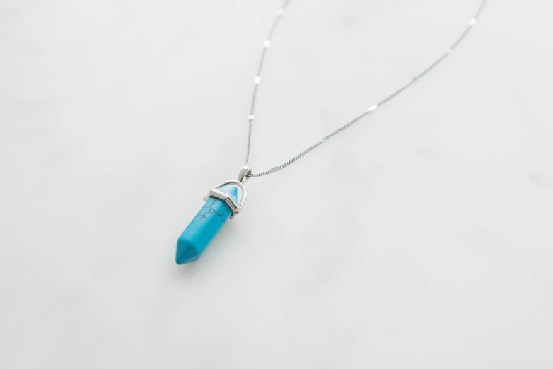 a blue rock pendant hangs from a chain