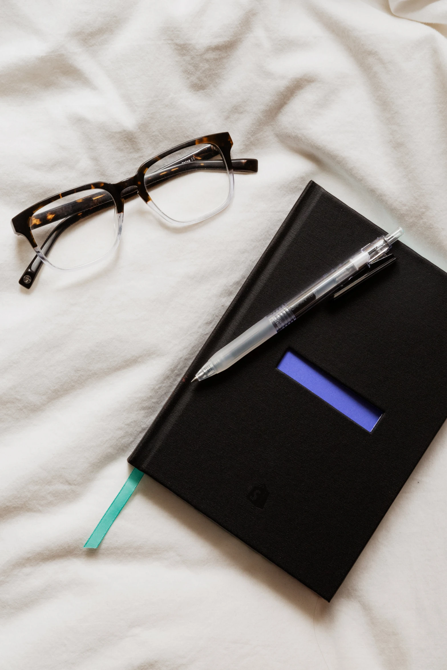 an object on a bed with glasses and note pad