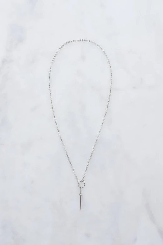 the long silver charm on a chain is attached with a tiny ball