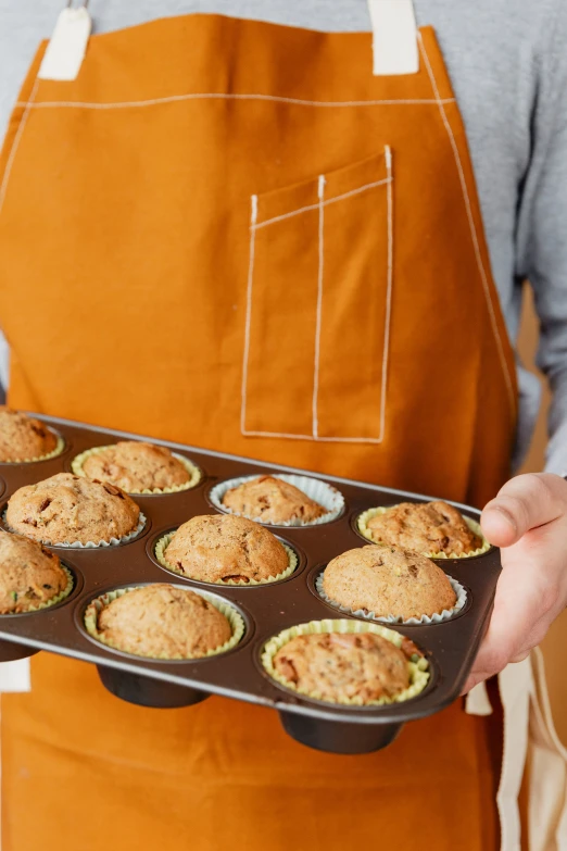 a baker holding out a muffin tin full of the best cupcakes ever