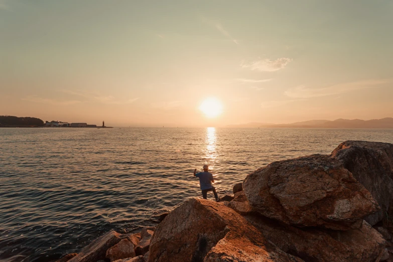 a man in the distance on a rocky shore next to the ocean