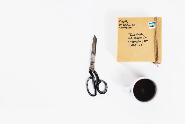 a paper, pen, scissors and cup on the counter