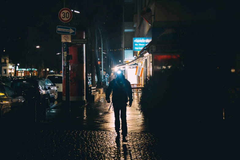 a man walking down a sidewalk under a street light