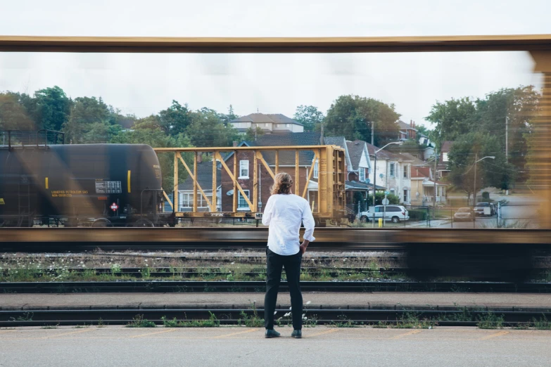 a woman standing on the platform with the train passing by