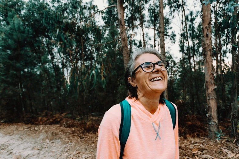 a woman with a backpack standing in front of trees