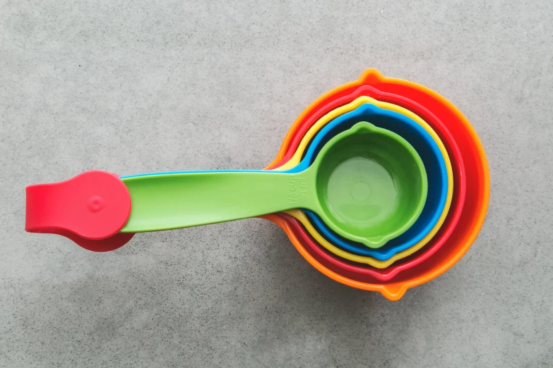 a colorful bowl has a plastic spoon near the center