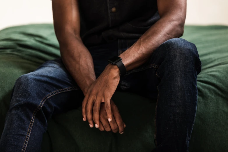 a man sitting on top of a couch with his hands clasped