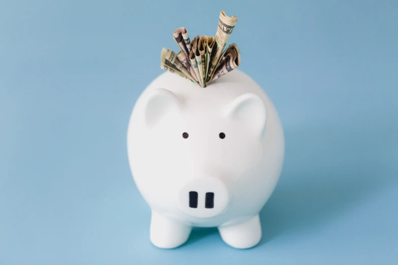 a white piggy bank with a money sticking out of it