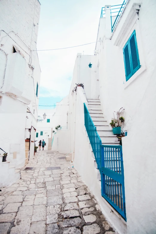 a narrow street with a blue door and railing