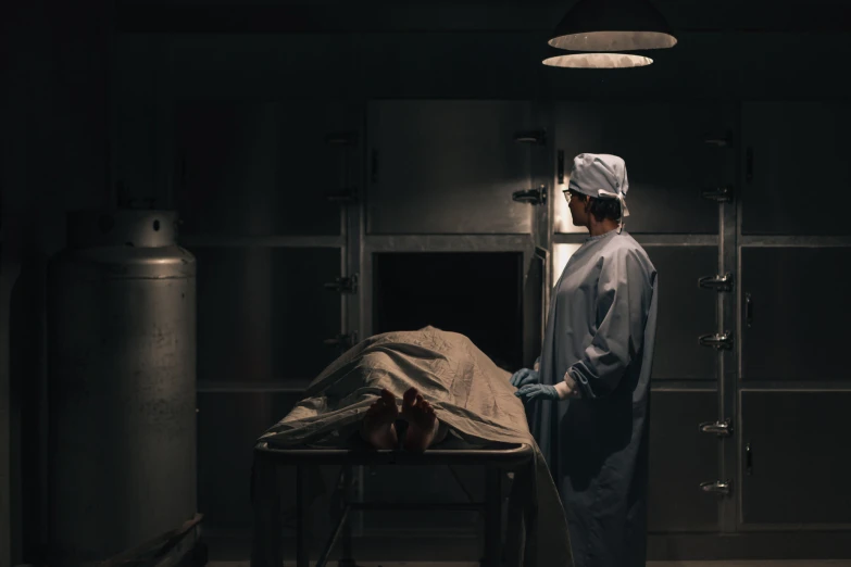 a surgeon standing at a table in a darkened room