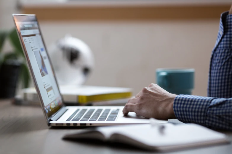 the person is typing on a laptop at the table