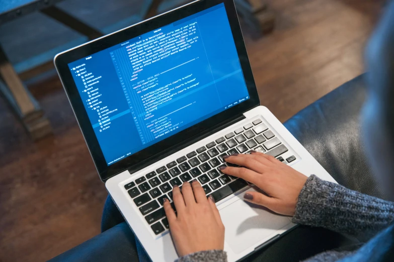 a person typing on a laptop while on the couch