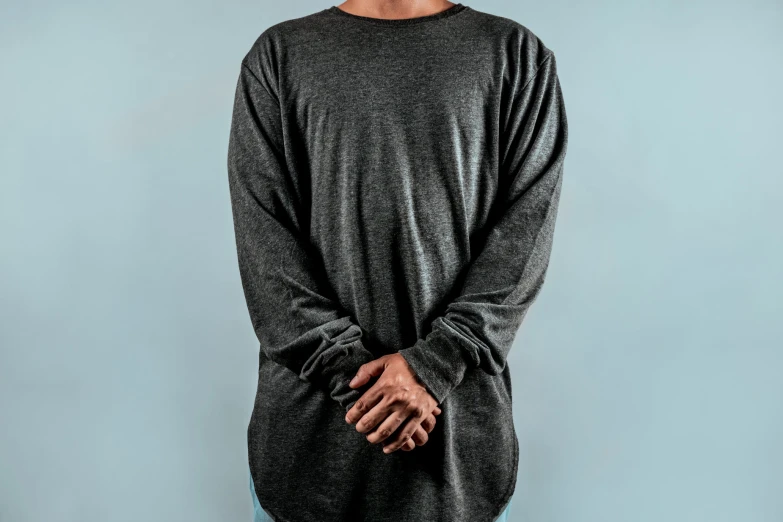 a young man poses for the camera in his gray shirt and blue jeans