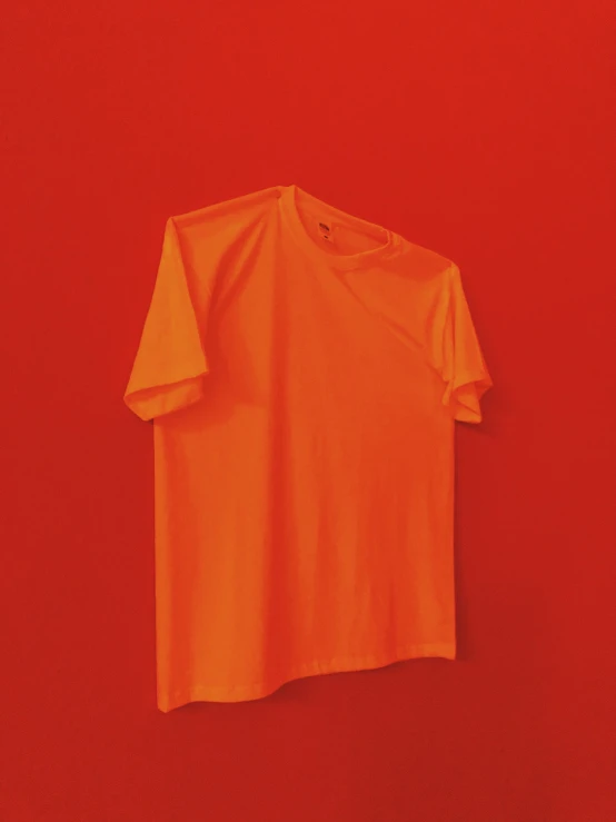 an orange tshirt hanging on a red wall