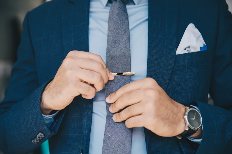 a person in suit and tie tying a tie