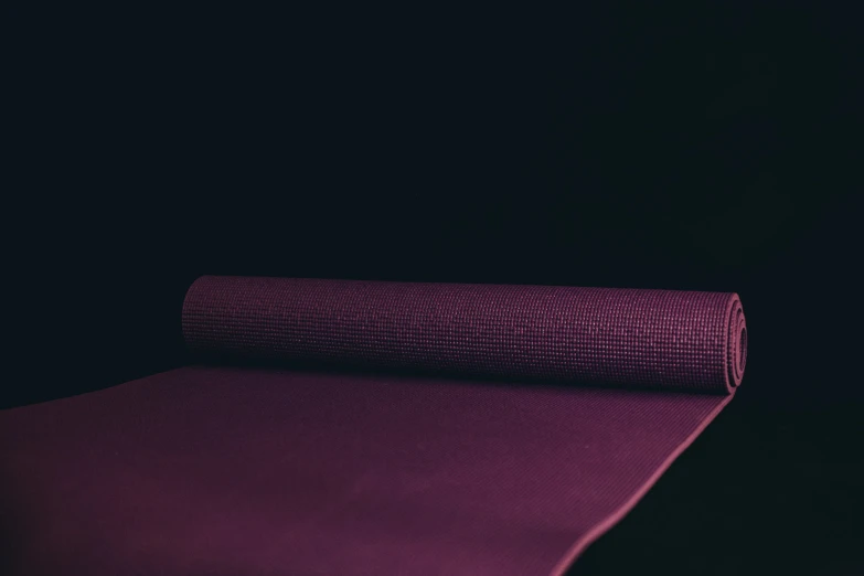 purple yoga mat on black background with light