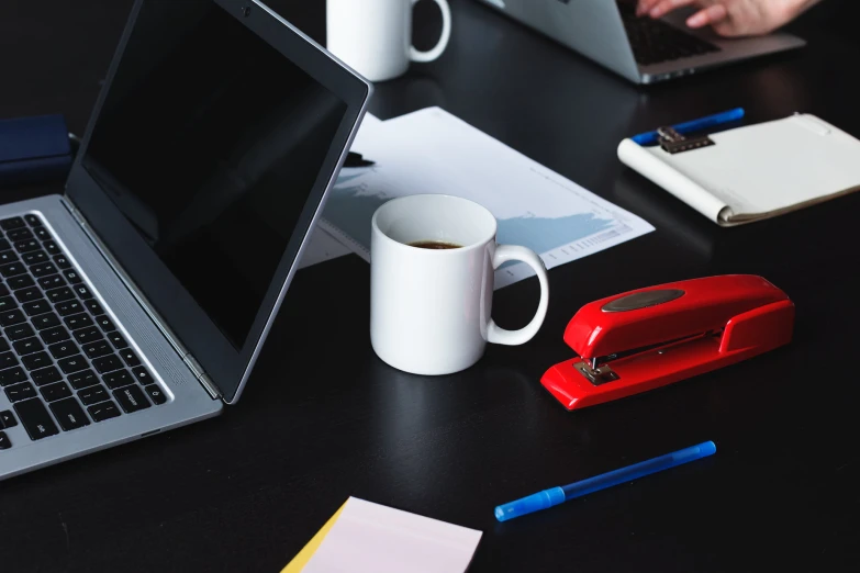 a table with two laptop computers, pens, and cups on it