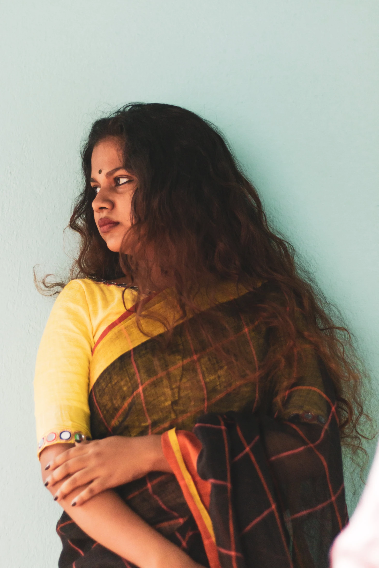 a woman with her arms crossed standing against a blue wall