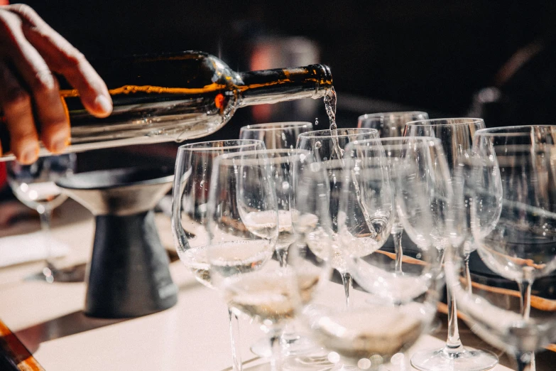 a person pouring a glass full of wine to many other glasses