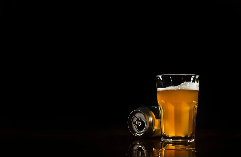 a can and glass of beer sitting on a table