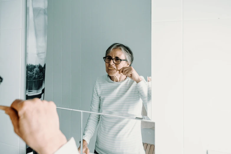 a woman in glasses standing in front of a mirror