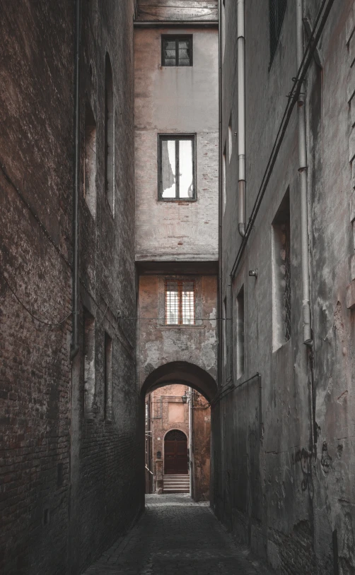 a dark alley with white windows and brick buildings