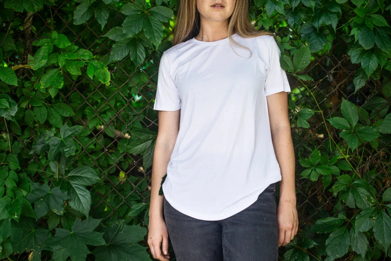 a woman standing by a vine with a white t - shirt on