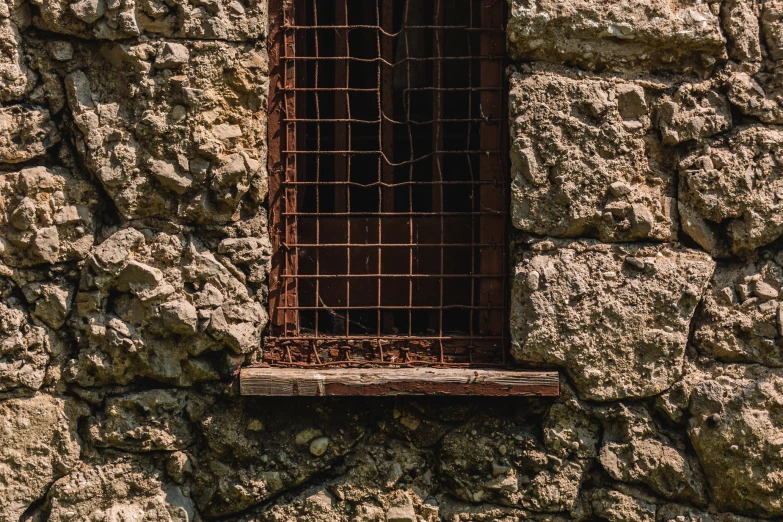 a small window frame is on the side of a stone wall