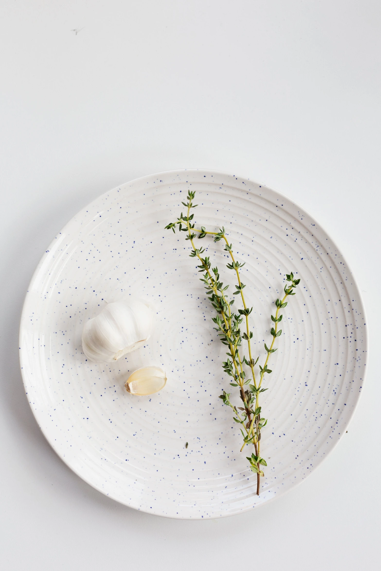 an unpeeled garlic on a plate with sprig