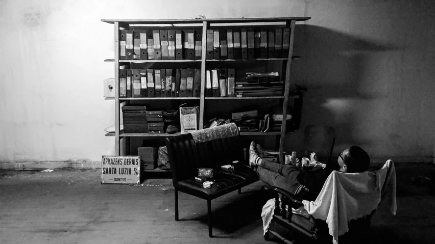 a lady sitting in a chair looking at some boxes and papers