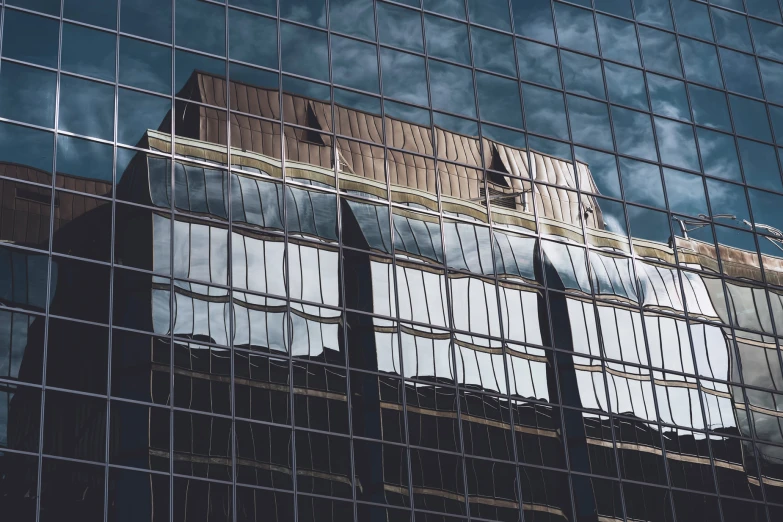 a tall building reflecting in the windows of another building