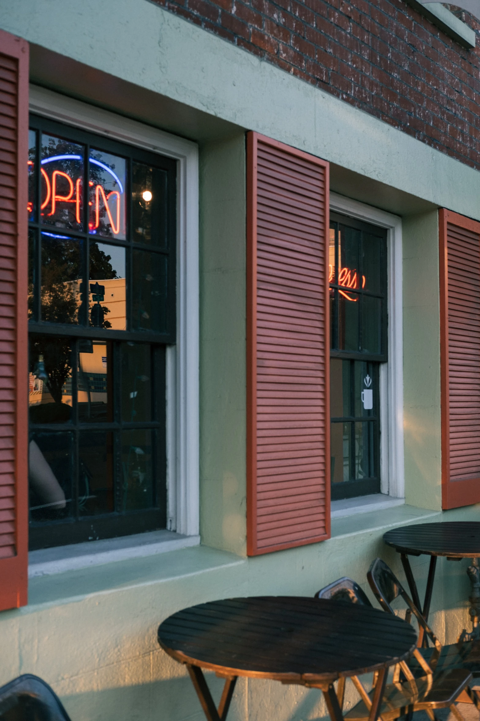 a row of tables outside of the front window of an establishment