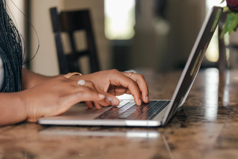 a woman is on her laptop typing on a table