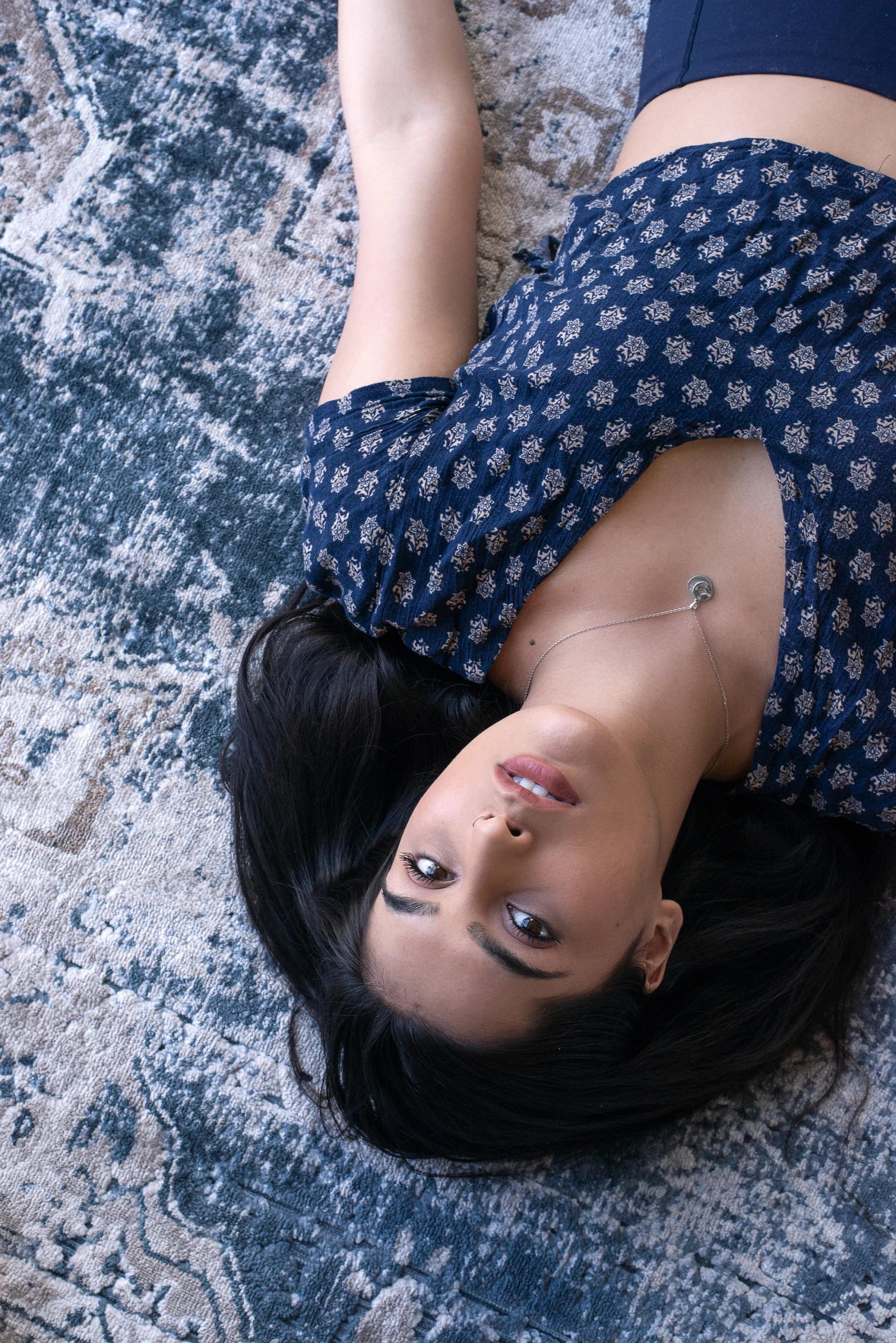 an asian girl in a blue dress lays on the carpet